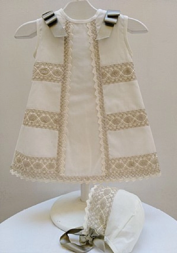 Faldón con capota en batista con puntillas.