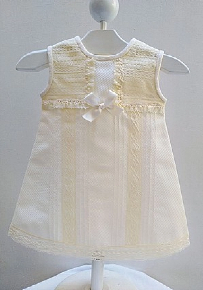 Faldón en piqué crudo con puntillas.